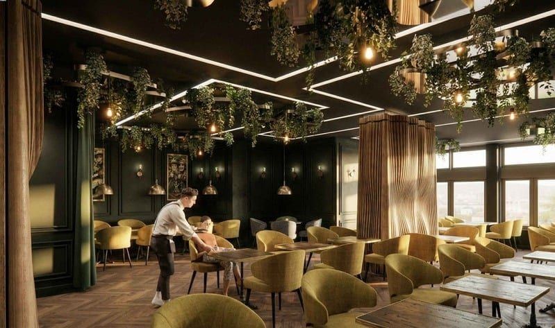 Waiter serving a seated guest among yellow velvet armchairs